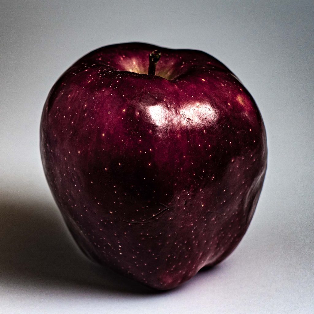 A dark, moody photograph of an apple.